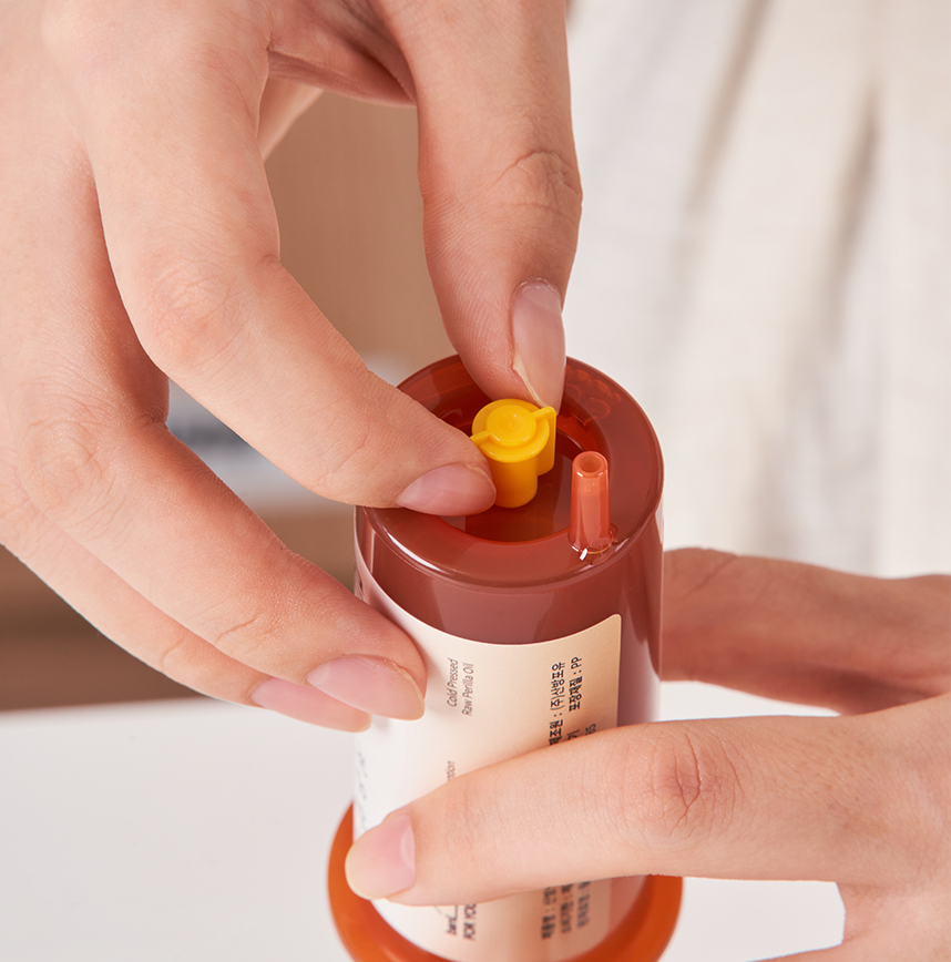 Person holding a small red container with a yellow cap
