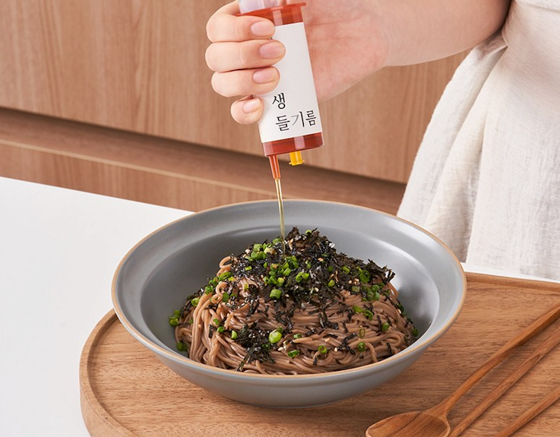 Person pouring perilla oil into noodles